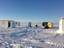 Photo of a frozen lake with ice fishing huts